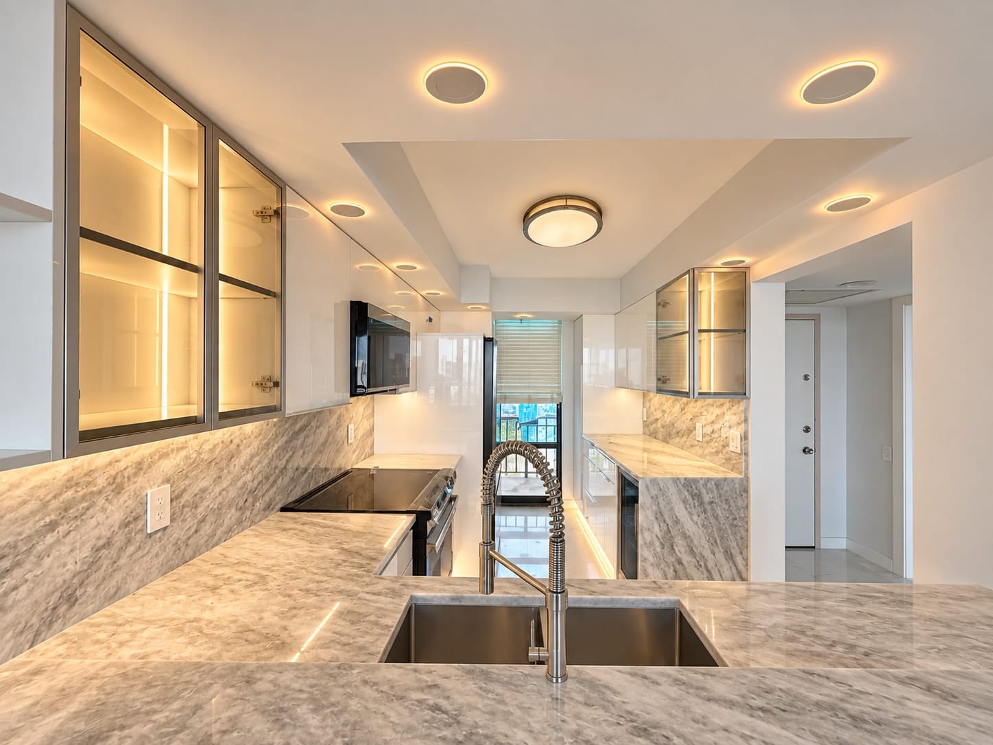 Bright custom kitchen with glass display cabinets, white gloss fronts and a marble counter